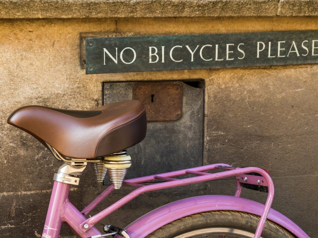 pink bicycle parked beside brown concrete wall