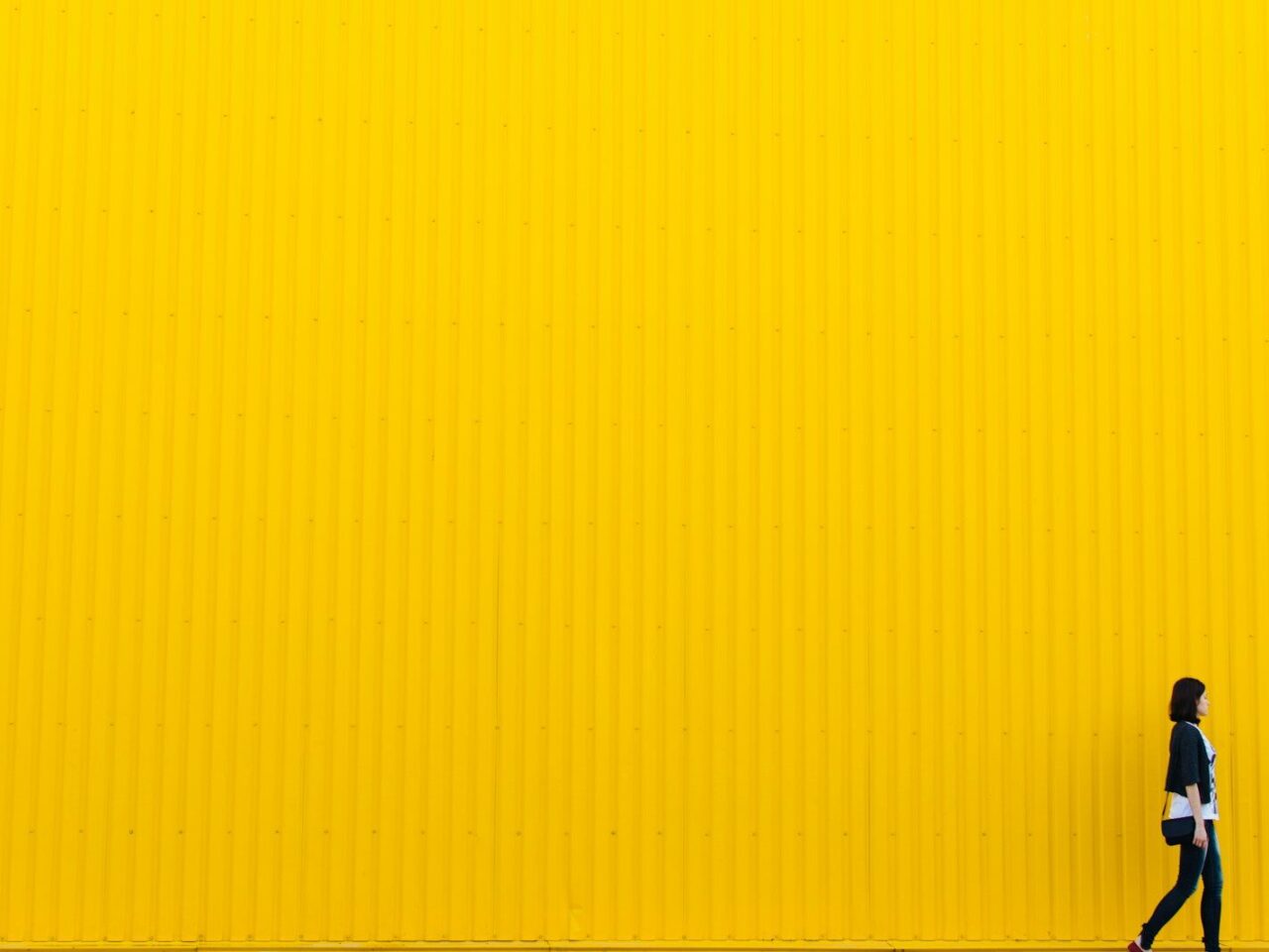 woman wearing black top standing near yellow wall