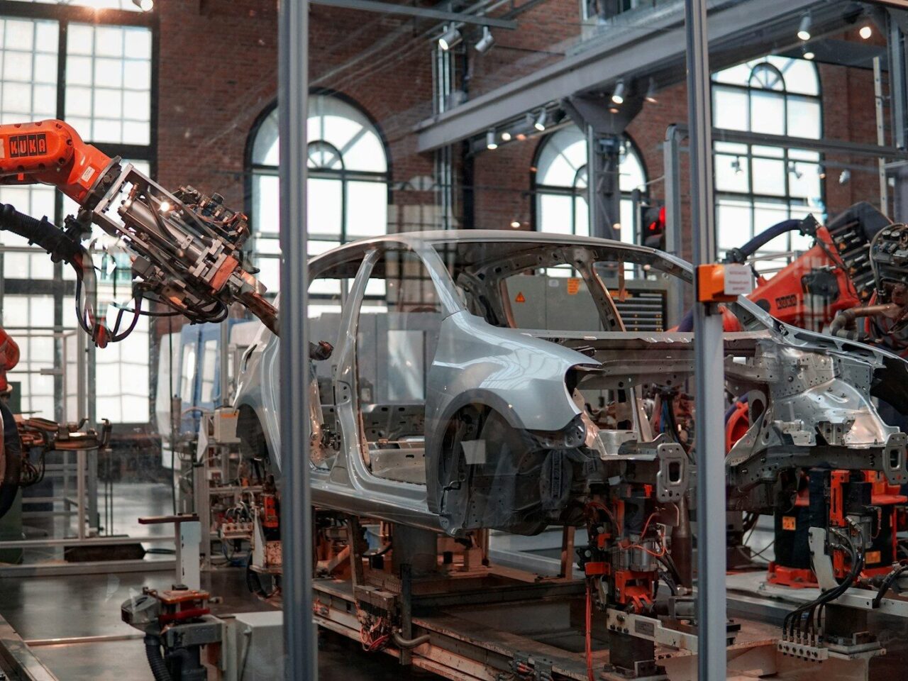 gray vehicle being fixed inside factory using robot machines
