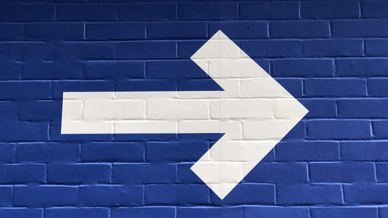 white arrow painted on brick wall