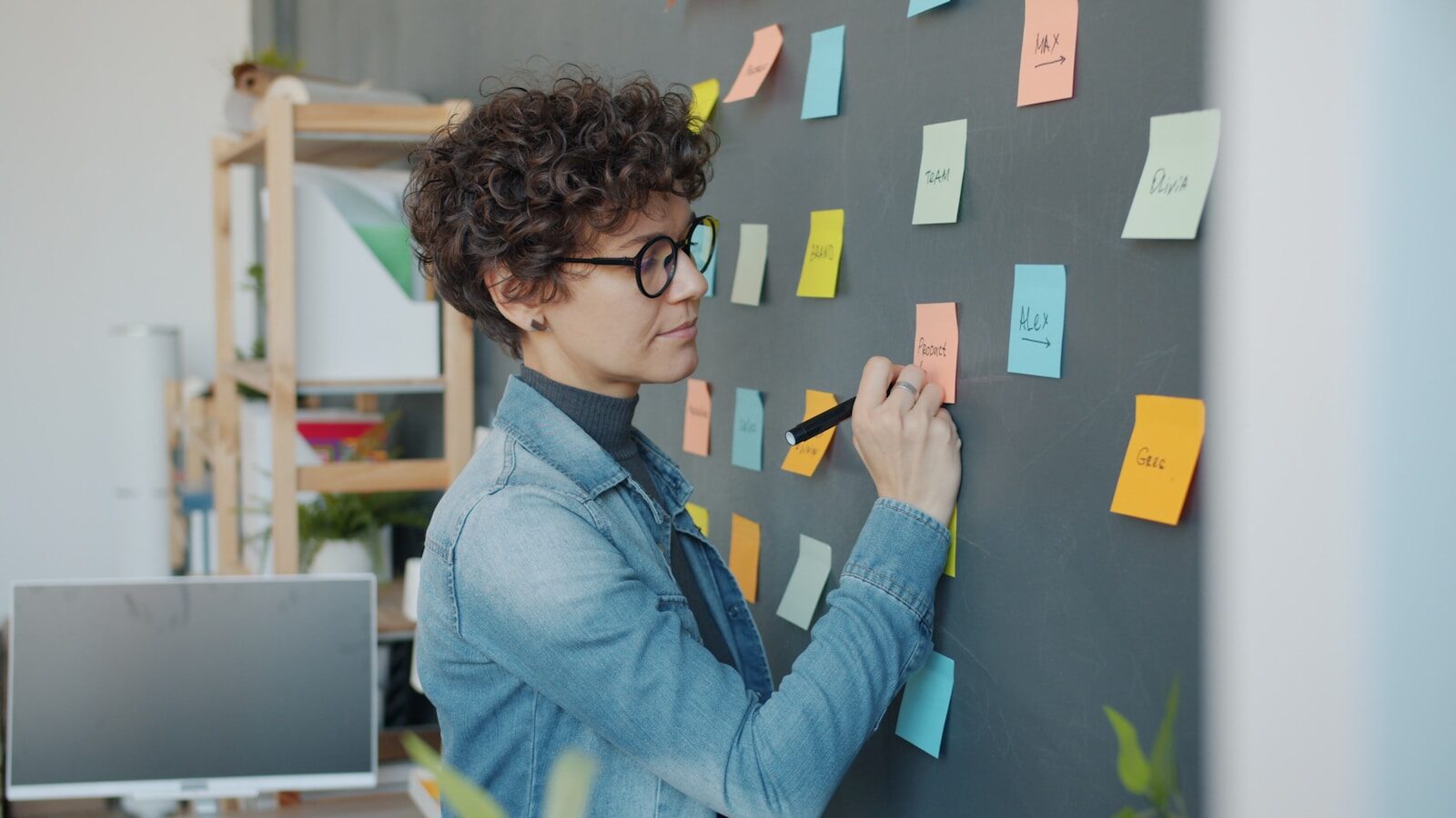 Woman writing on sticky notes on a wall.