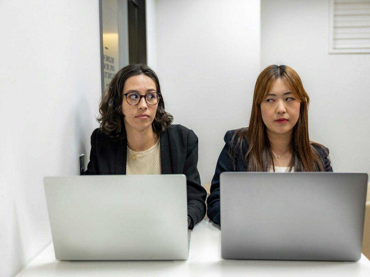 two women sitting at a table with laptops